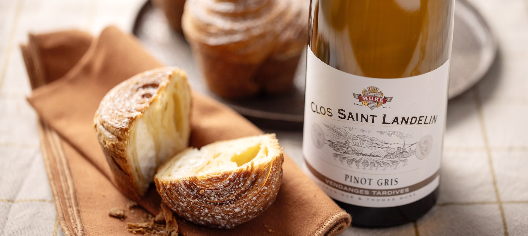 Butelka wina Clos Saint Landelin Pinot Gris od Domaine Muré obok świeżego pieczywa