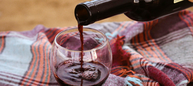 Otwarta butelka czerwonego wina nalewanego do kieliszka – wino gotowe do degustacji