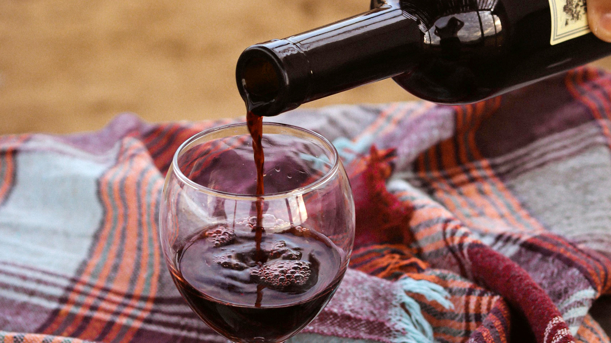 Otwarta butelka czerwonego wina nalewanego do kieliszka – wino gotowe do degustacji